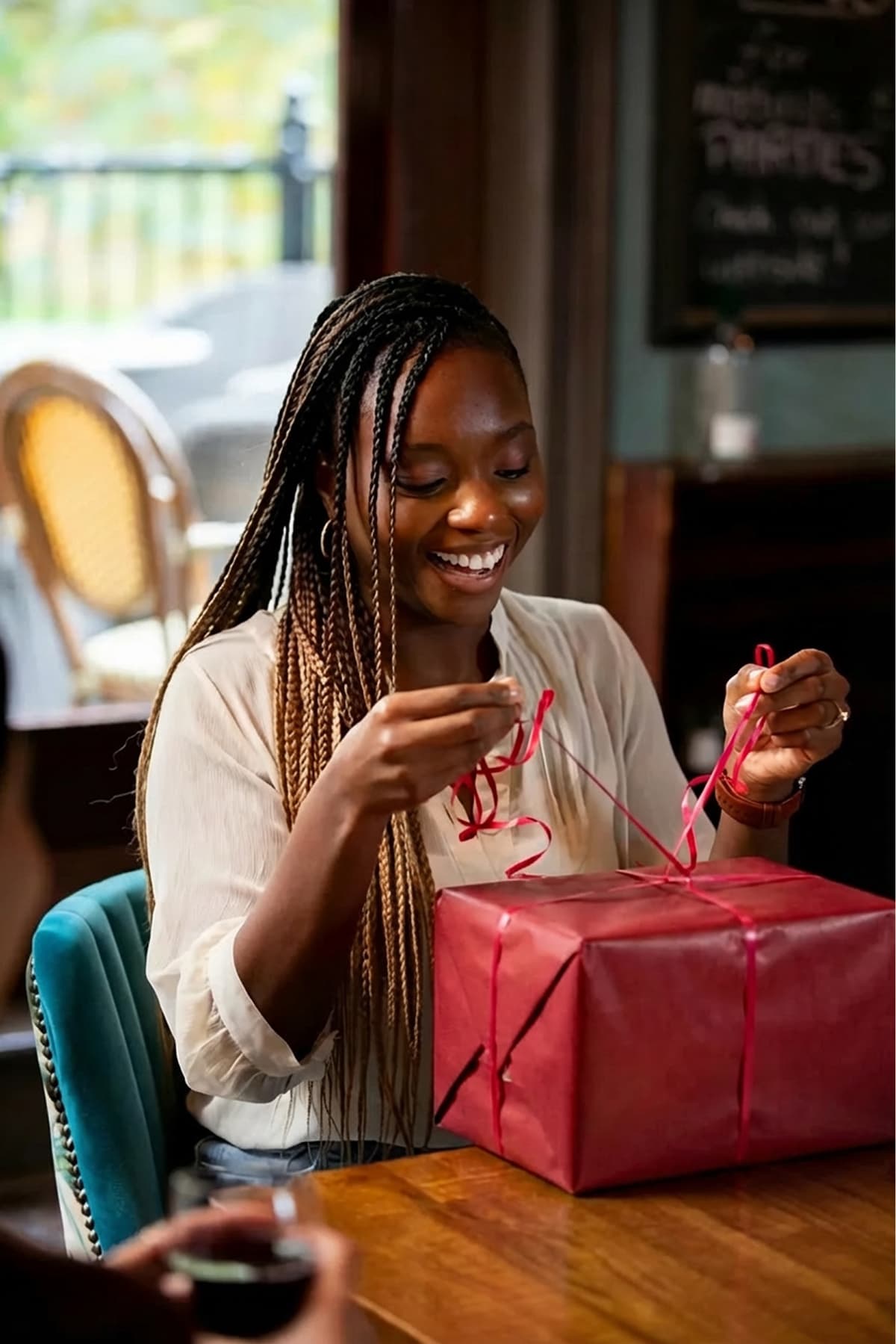 Person browsing their wishlist on a phone with a wrapped gift beside them